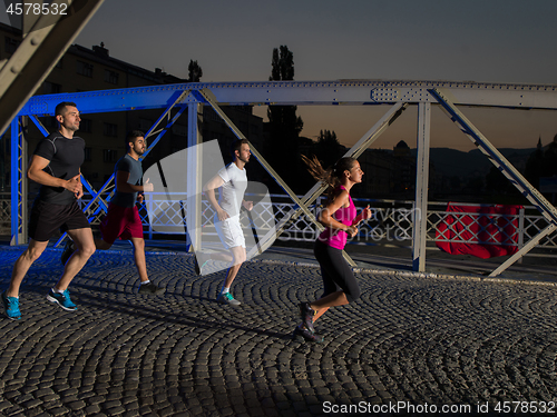 Image of young people jogging across the bridge