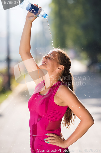 Image of woman pouring water from bottle on her head