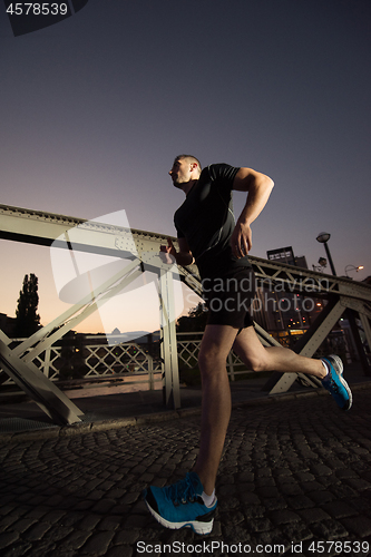 Image of man jogging across the bridge in the city