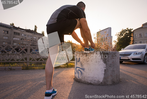 Image of man tying running shoes laces