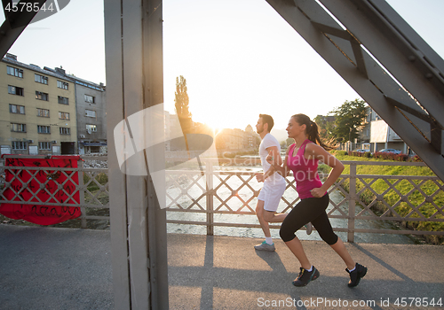 Image of young couple jogging across the bridge in the city