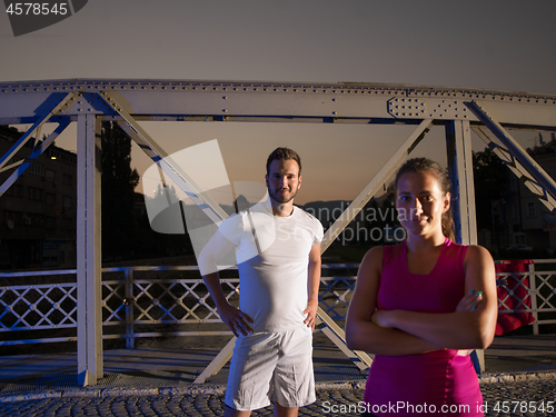 Image of portrait of couple jogging across the bridge in the city