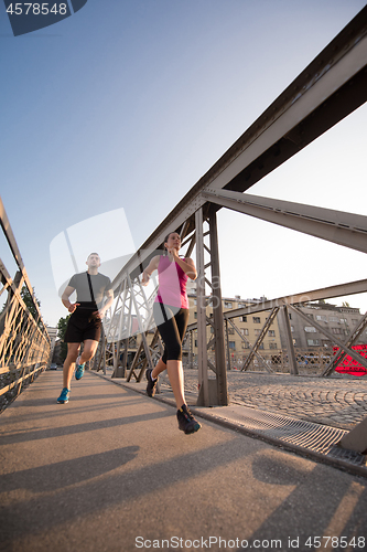 Image of young couple jogging across the bridge in the city