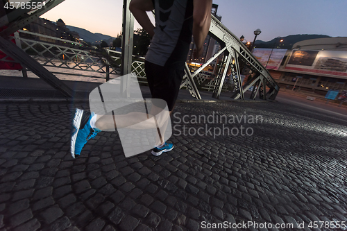 Image of man jogging across the bridge in the city