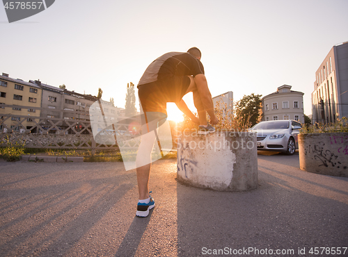 Image of man tying running shoes laces