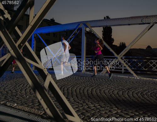 Image of portrait of couple jogging across the bridge in the city