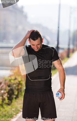 Image of man pouring water from bottle on his head