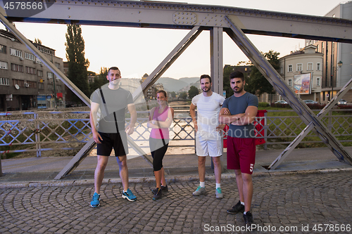 Image of group of young people jogging across the bridge