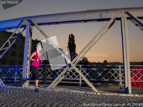 Image of woman jogging across the bridge in the city