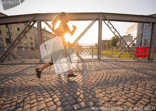 Image of woman jogging across the bridge at sunny morning