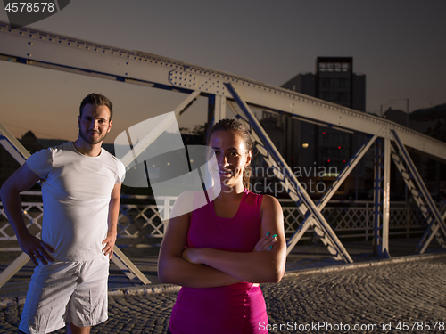 Image of portrait of couple jogging across the bridge in the city