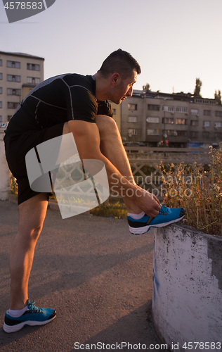 Image of man tying running shoes laces