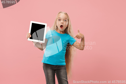 Image of Little funny girl with tablet on pink background