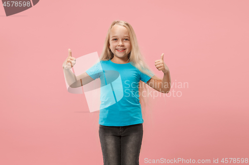 Image of The happy teen girl standing and smiling against pink background.