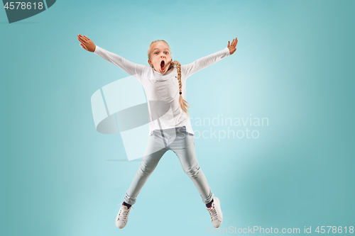 Image of Adorable small child at blue studio. The girl is jumping and smiling.