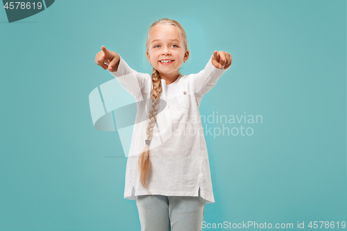 Image of The happy teen girl pointing to you, half length closeup portrait on blue background.