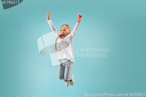 Image of Adorable small child at blue studio. The girl is jumping and smiling.