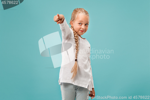 Image of The happy teen girl pointing to you, half length closeup portrait on blue background.