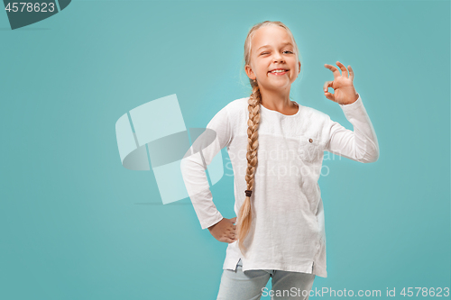 Image of The happy teen girl standing and smiling against blue background.