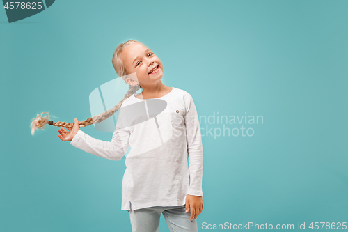 Image of The happy teen girl standing and smiling against blue background.