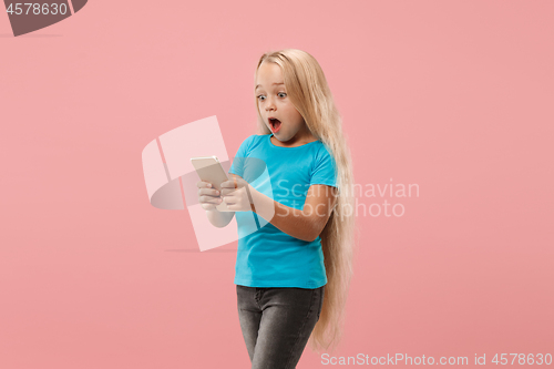 Image of The happy teen girl standing and smiling against pink background.