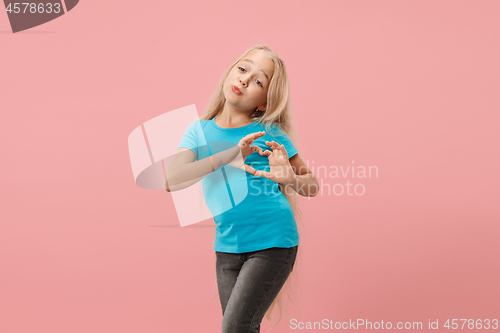 Image of Beautiful smiling teen girl makes the shape of a heart with her hands on the pink background.