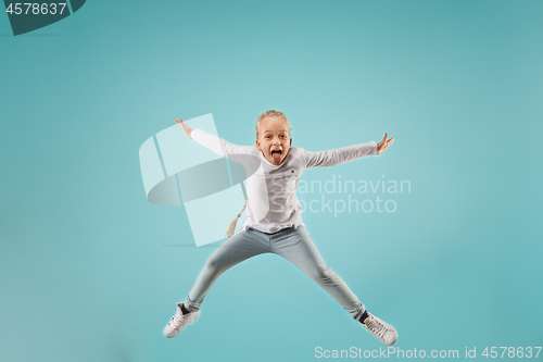 Image of Adorable small child at blue studio. The girl is jumping and smiling.