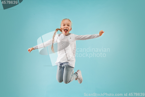 Image of Adorable small child at blue studio. The girl is jumping and smiling.