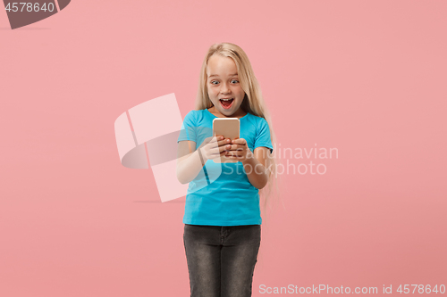 Image of The happy teen girl standing and smiling against pink background.