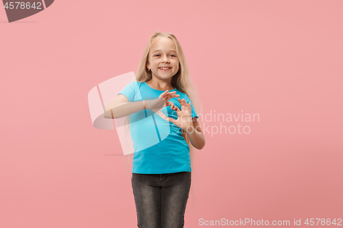 Image of Beautiful smiling teen girl makes the shape of a heart with her hands on the pink background.