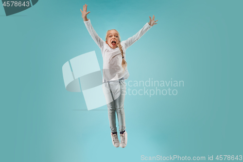 Image of Adorable small child at blue studio. The girl is jumping and smiling.