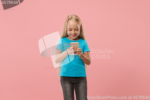 Image of The happy teen girl standing and smiling against pink background.