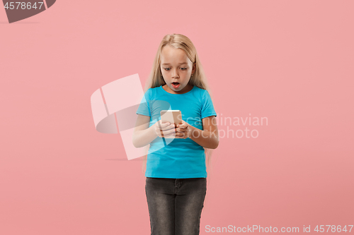 Image of The happy teen girl standing and smiling against pink background.