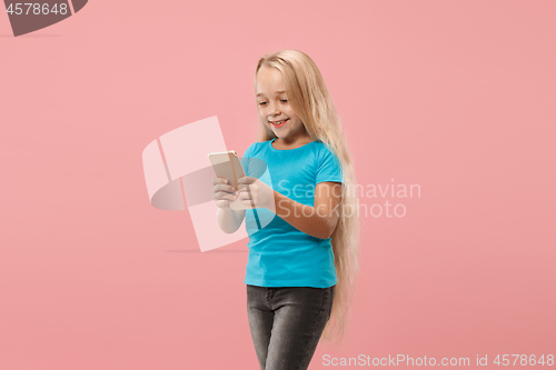 Image of The happy teen girl standing and smiling against pink background.