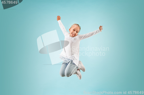 Image of Adorable small child at blue studio. The girl is jumping and smiling.