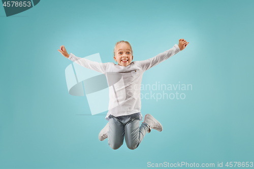 Image of Adorable small child at blue studio. The girl is jumping and smiling.