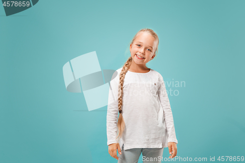 Image of The happy teen girl standing and smiling against blue background.