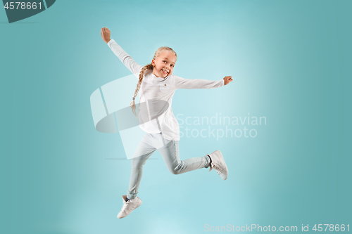 Image of Adorable small child at blue studio. The girl is jumping and smiling.