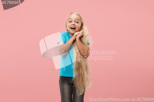 Image of The happy teen girl standing and smiling against pink background.