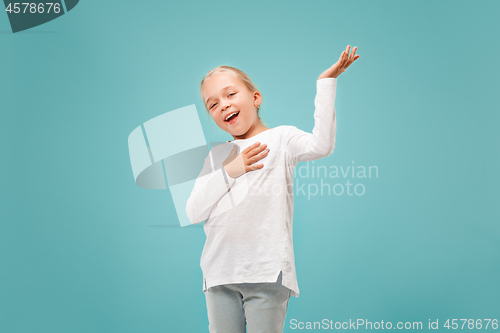 Image of The happy teen girl standing and smiling against blue background.