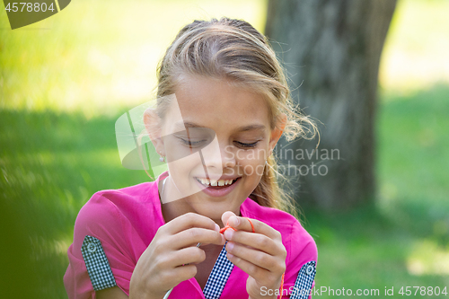 Image of Portrait of a girl who knits on a knitting needles on a picnic in nature, close-up