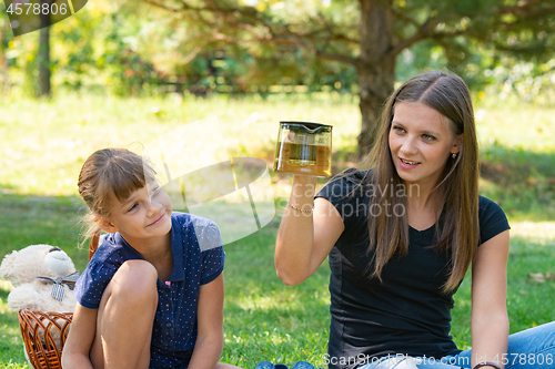 Image of Girl and girl have fun at a teapot at a picnic