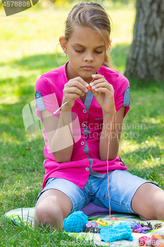 Image of Girl knits on a knitting needles on a picnic in nature