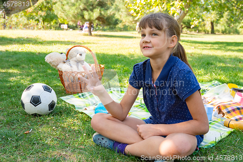 Image of Girl on a picnic counts goals scored on fingers