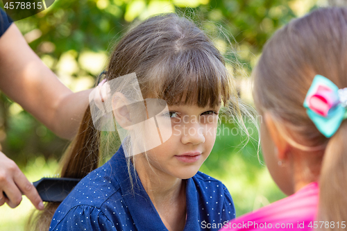 Image of Girl trying to comb the girl\'s tightly tangled hair
