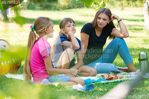 Image of Sisters of different ages talking cute on a picnic