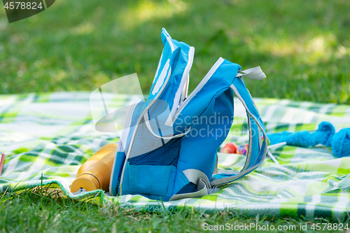 Image of Children\'s backpack and bottle for water lie on a bedspread on a picnic