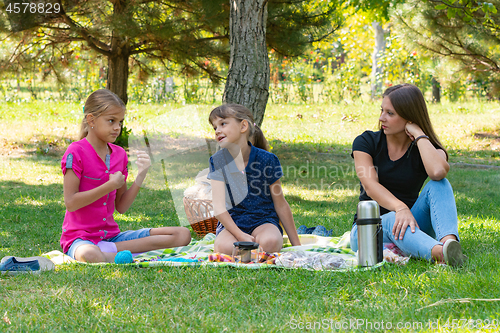 Image of Two girls and a girl talking on a picnic