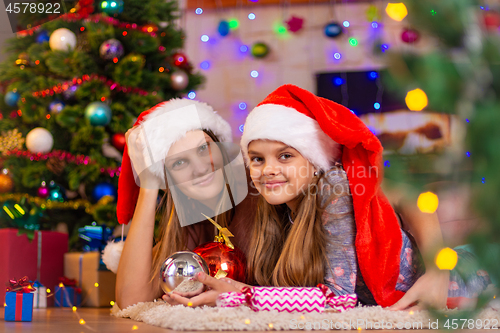 Image of Girl and child lie on the mat in the New Year\'s interior