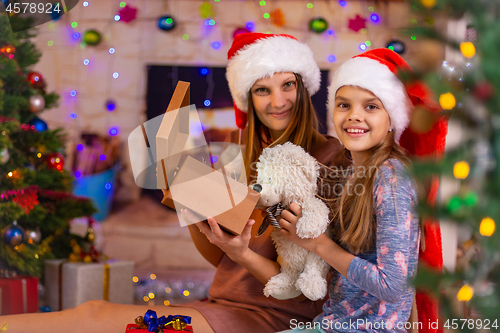 Image of Mom and daughter opened the Christmas box with a gift and looked into the frame